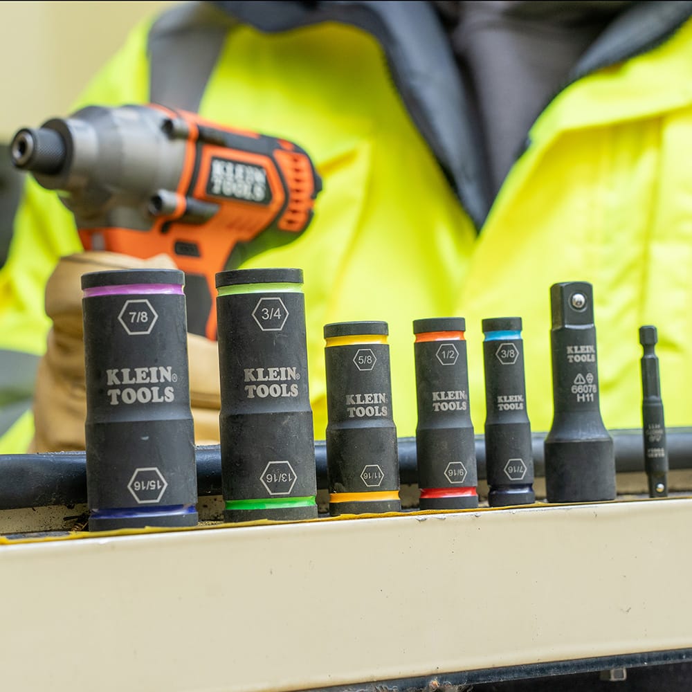 Five Klein flip impact sockets stood in a row next to the 66078 large adapter and 66079 small adapter on a utility workbench.