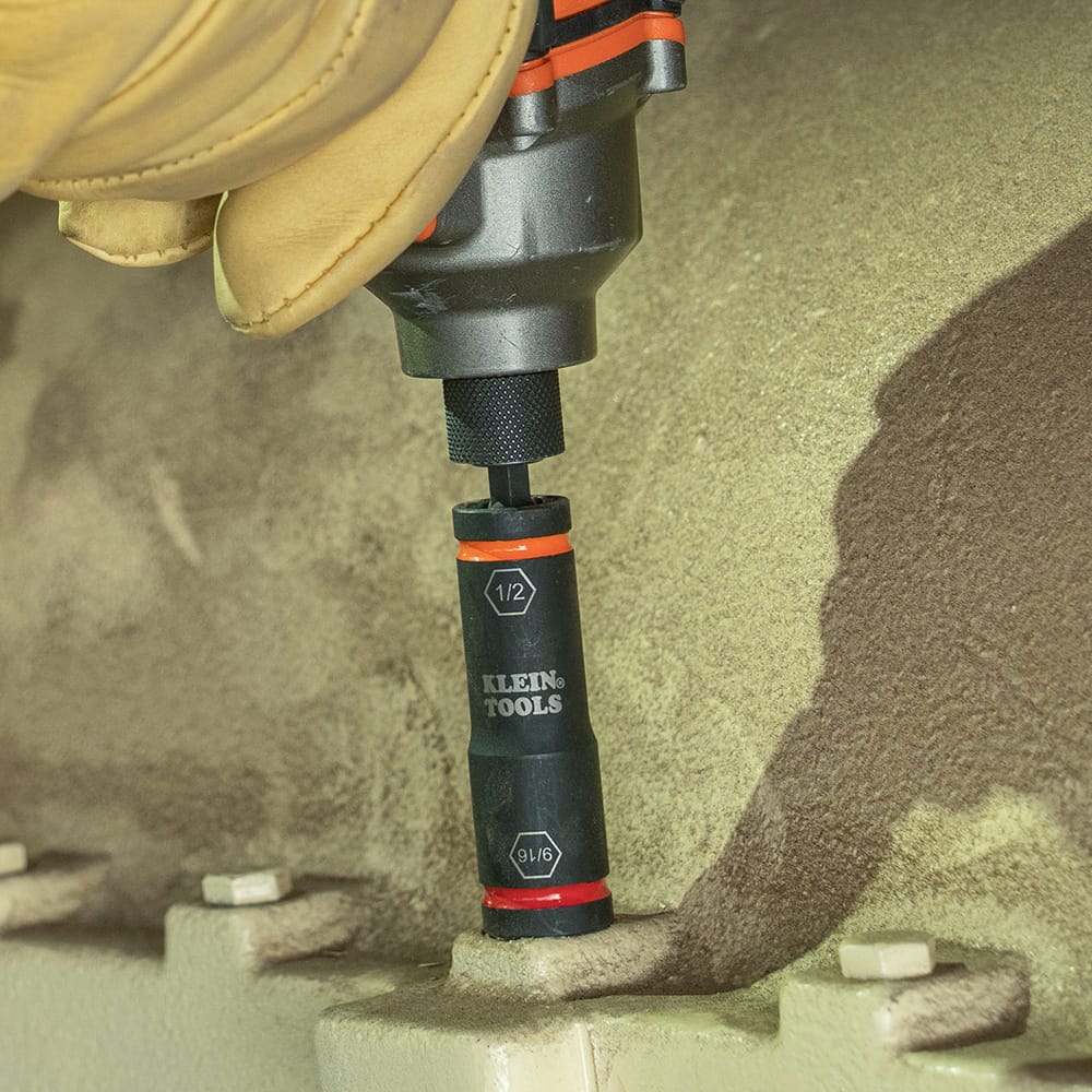 Technician driving a machine bolt using a cordless impact driver fitted with a Klein flip socket and 66079 small adapter.