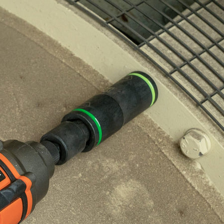 Electrician aligning a green color-coded 3/4 by 13/16-inch Klein flip socket on an impact driver to fasten industrial structural bolts.
