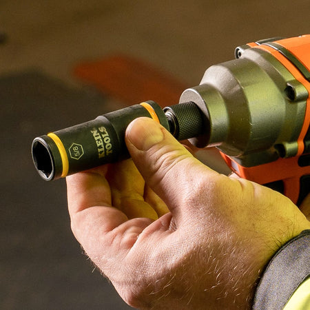 Worker swapping socket ends on a 1/4-inch hex impact driver chuck to quickly engage a 5/8-inch bolt head.