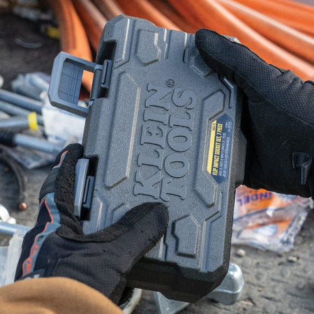 Gloved worker holding the closed molded carrying case containing the complete Klein 66070 impact flip socket set.