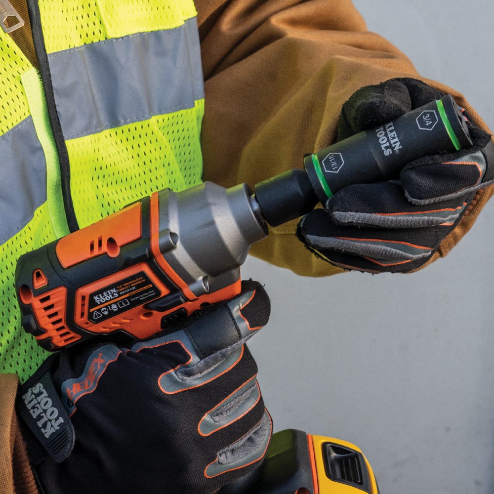 Close-up of a worker swapping socket ends on a Klein 1/2-inch impact wrench to transition between 3/4 and 13/16-inch hardware.