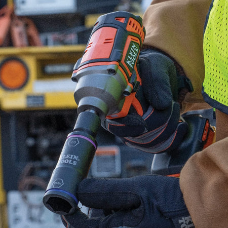 Lineman operating a cordless impact wrench fitted with the 7/8 by 15/16-inch Klein flip socket on outdoor utility hardware.