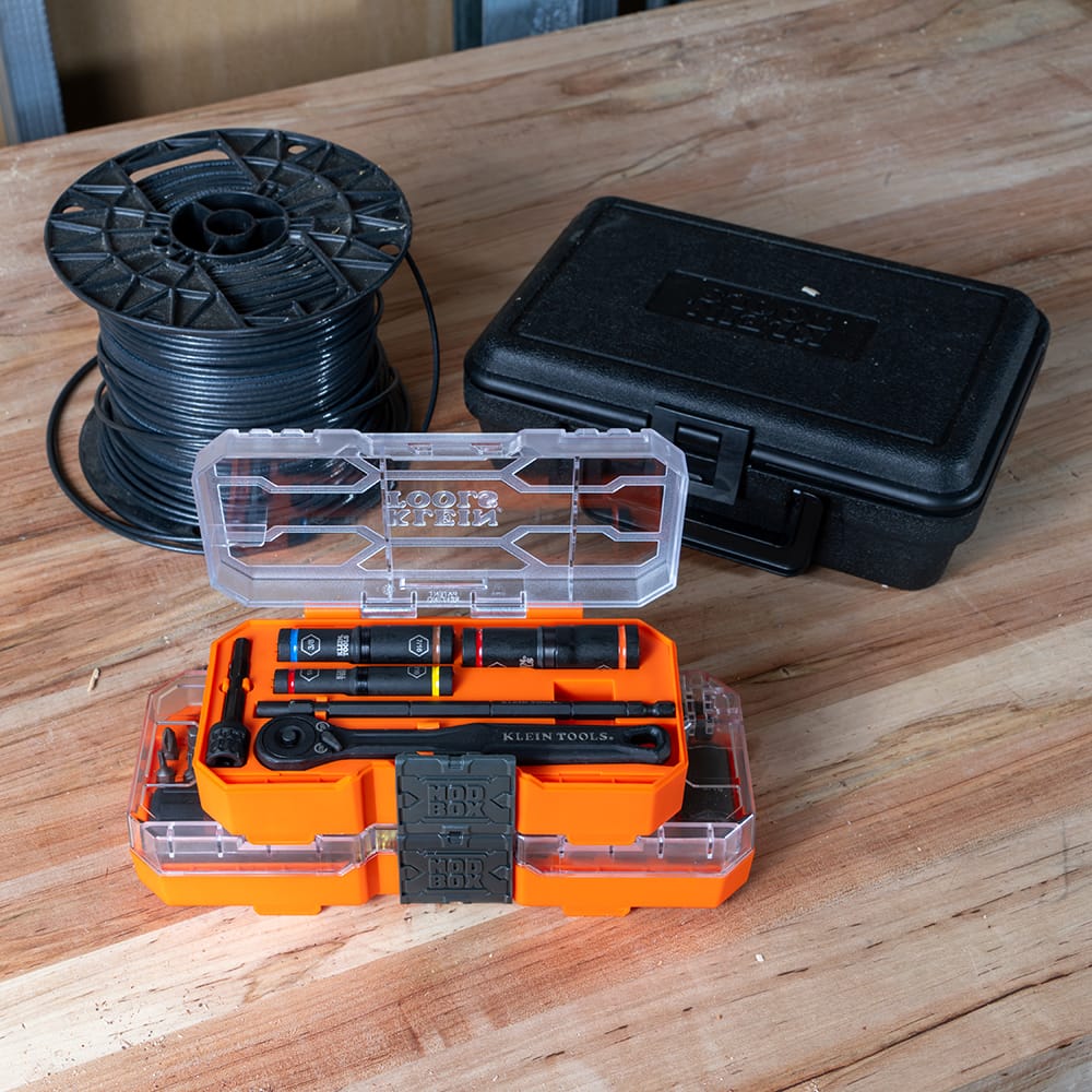Klein 65238 MODbox storage case stacked on top of a matching tool case on a workbench next to an electrical wire spool.