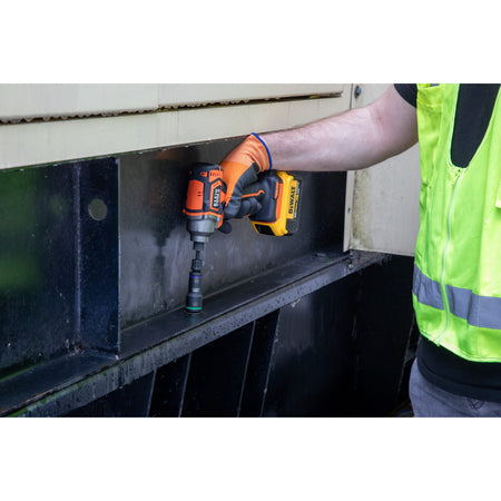 Worker using an impact driver with a Klein 3/4-inch flip socket to fasten a structural steel beam bolt on an industrial equipment housing.