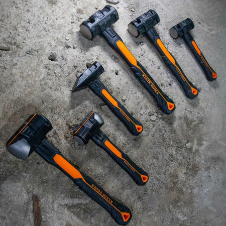 A set of Klein striking tools, including various sledgehammers and the H80602 blacksmith hammer, laid out diagonally on a concrete surface, showing the range of hammer weights and handle designs.