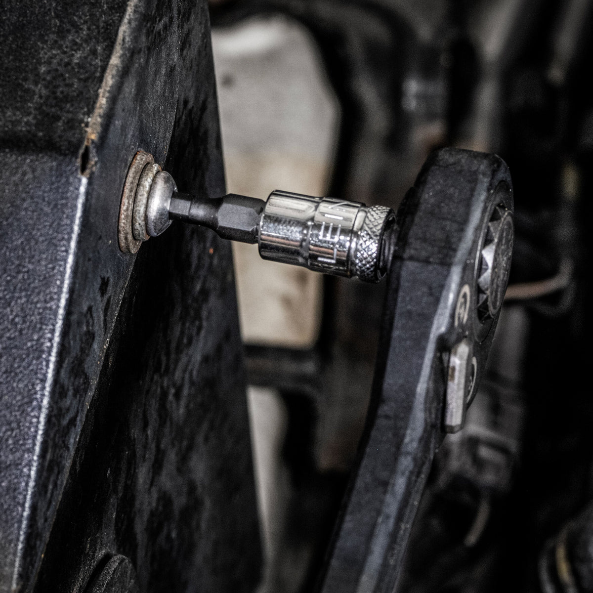 Mechanic using a pass-through ratchet and Klein knurled hex bit socket to turn a flush fastener in a tight automotive engine space.