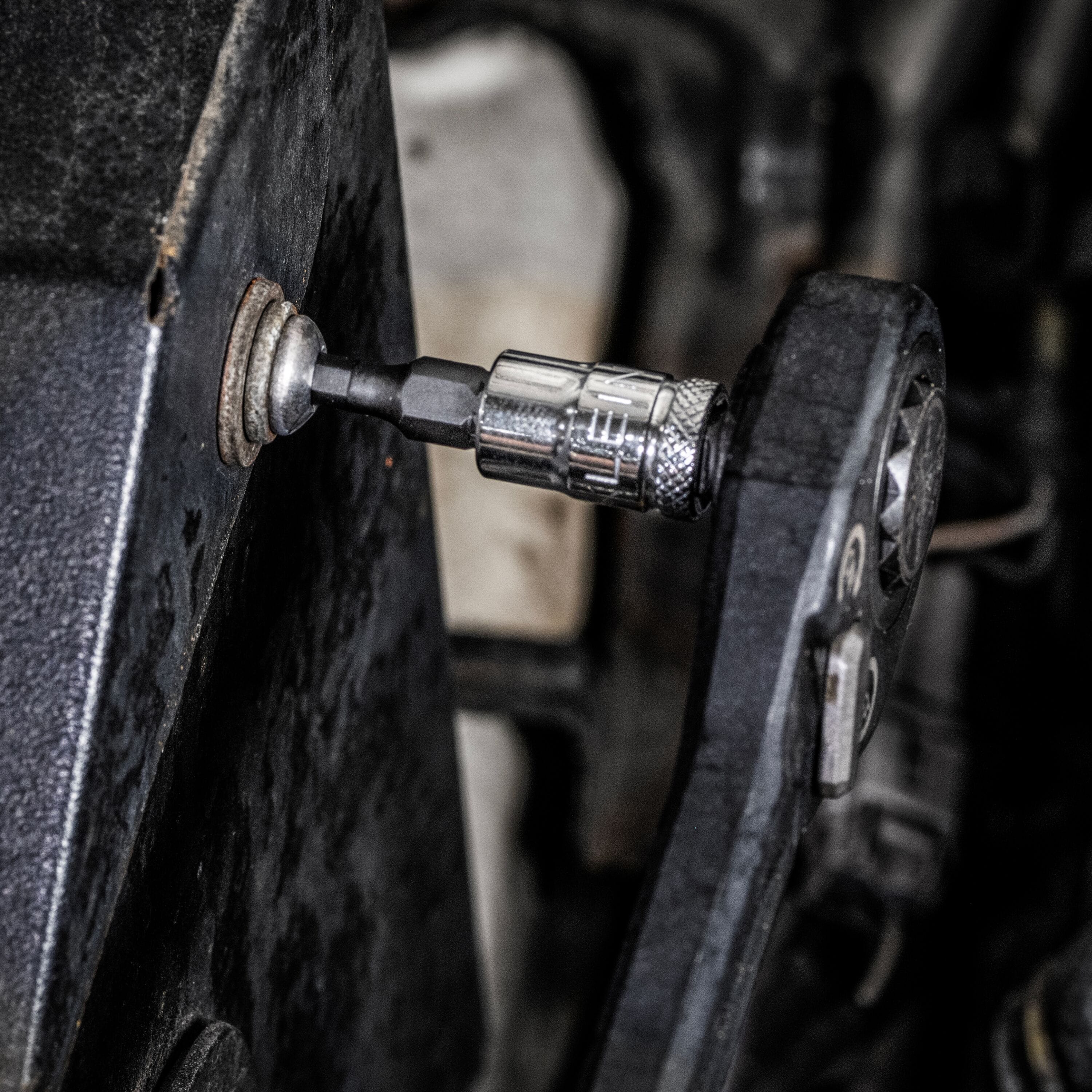 Mechanic using a pass-through ratchet and Klein knurled hex bit socket to turn a flush fastener in a tight automotive engine space.