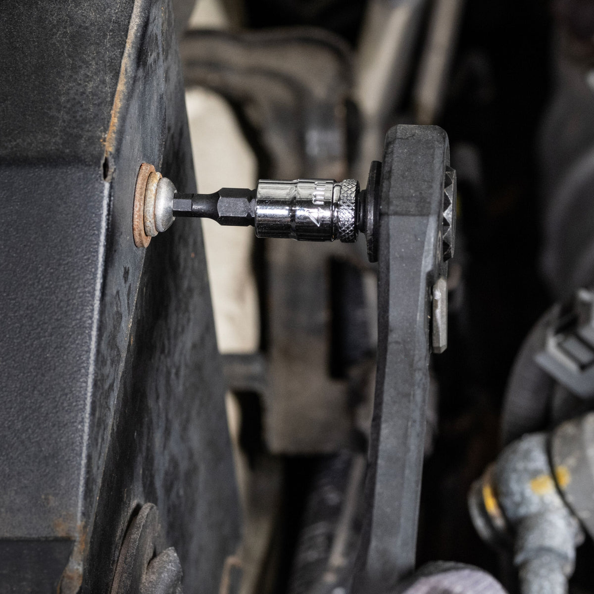 Mechanic using a ratchet fitted with a Klein 4 mm hex bit socket to remove an internal hex fastener from an engine bay housing.