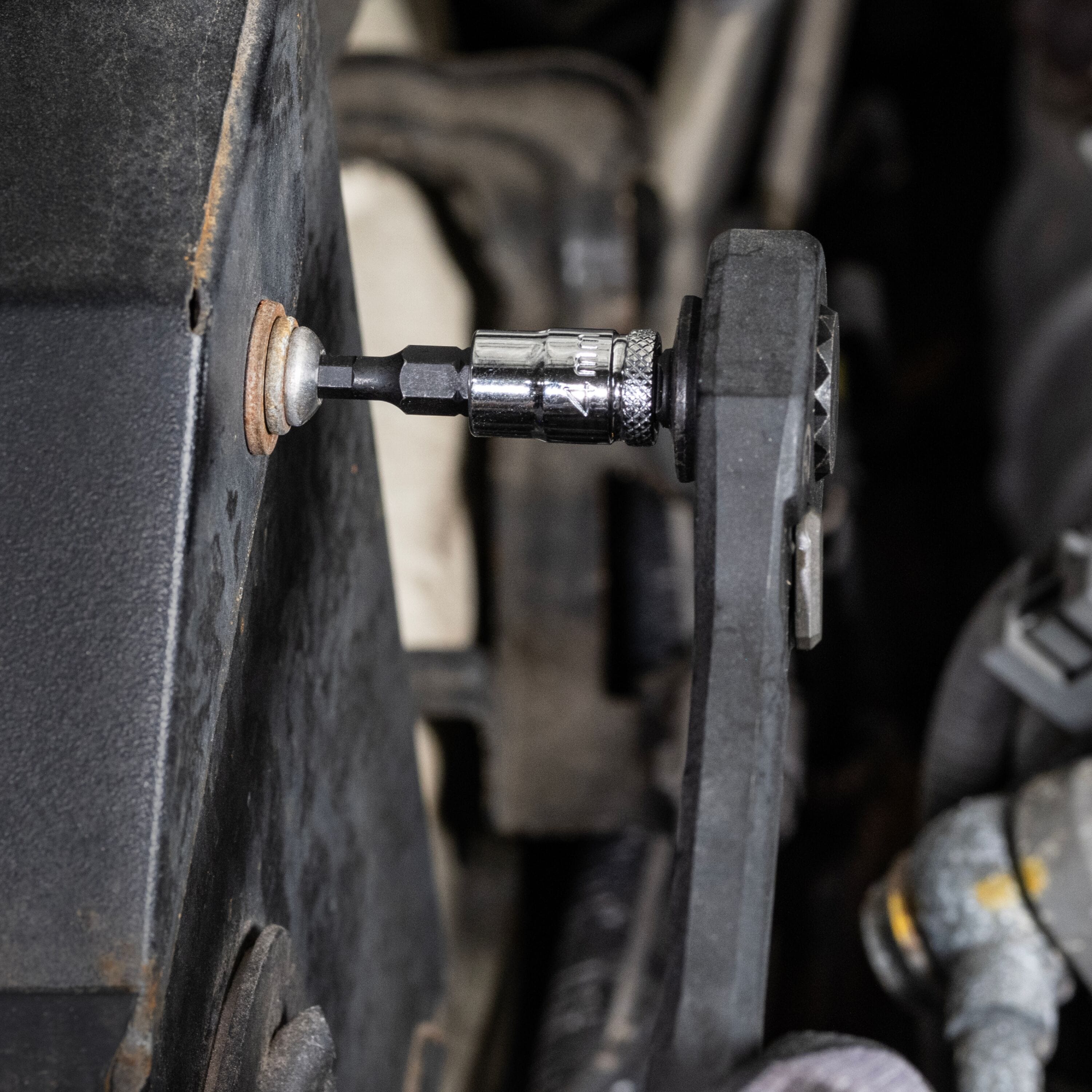 Mechanic using a ratchet fitted with a Klein 4 mm hex bit socket to remove an internal hex fastener from an engine bay housing.