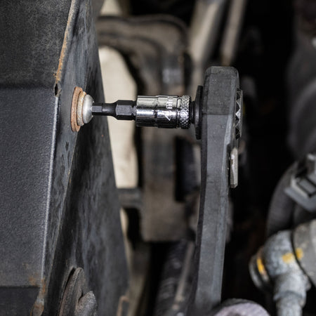 Mechanic using a ratchet fitted with a Klein 4 mm hex bit socket to remove an internal hex fastener from an engine bay housing.