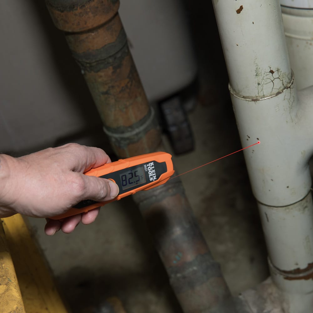 Action shot demonstrating the IR07 probe measuring liquid temperature in a copper pipe system. The technician is shown probing the fluid directly, while the digital display provides a rapid, accurate reading for system troubleshooting.