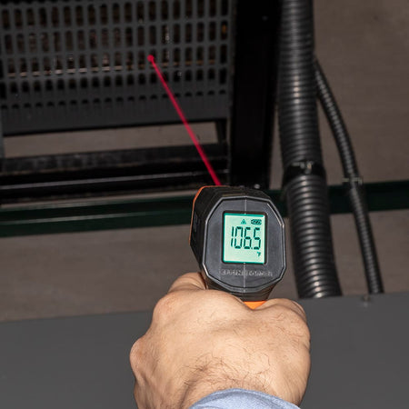 Top-down view of the Klein Tools IR1 focusing on the measurement aperture and targeting laser output. The image emphasizes the safety warnings and the precise alignment required for non-contact temperature diagnostics on electrical components.