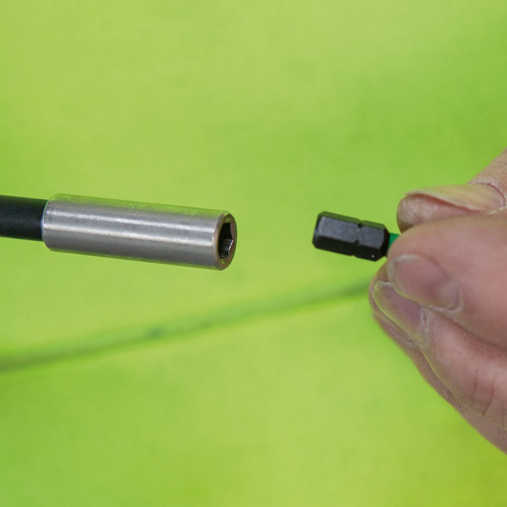 Technician aligning a 1/4-inch hex driver bit into the magnetic receiver collar of the Klein 32791 4-inch extension shaft.