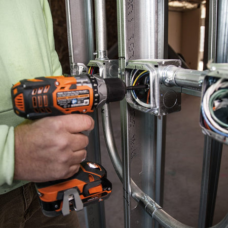 Electrician using a power drill with the Klein 32791 4-inch extension to reach terminal screws inside a deep metal junction box.