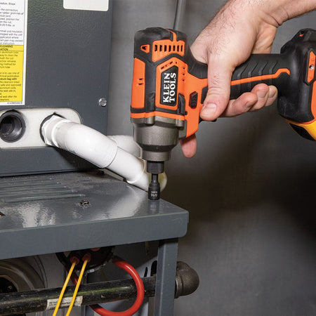 Technician using a Klein impact driver with a 5/16-inch magnetic nut driver to secure sheet metal screws on an HVAC unit panel.