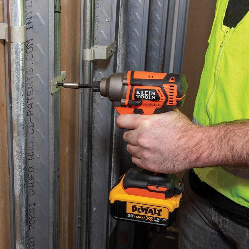 Electrician using a power impact driver with the Klein 3-inch magnetic extension to fasten conduit clamps onto metal framing studs.