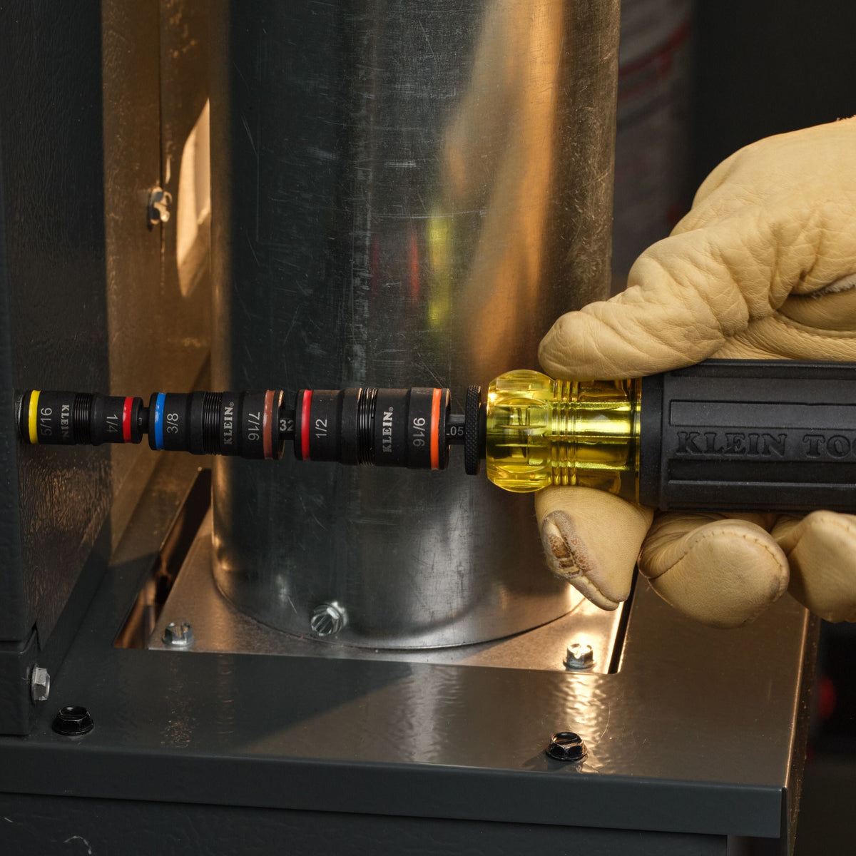 Technician using the Klein 32303HD manual driver to fasten sheet metal duct screws in a narrow HVAC clearance space.