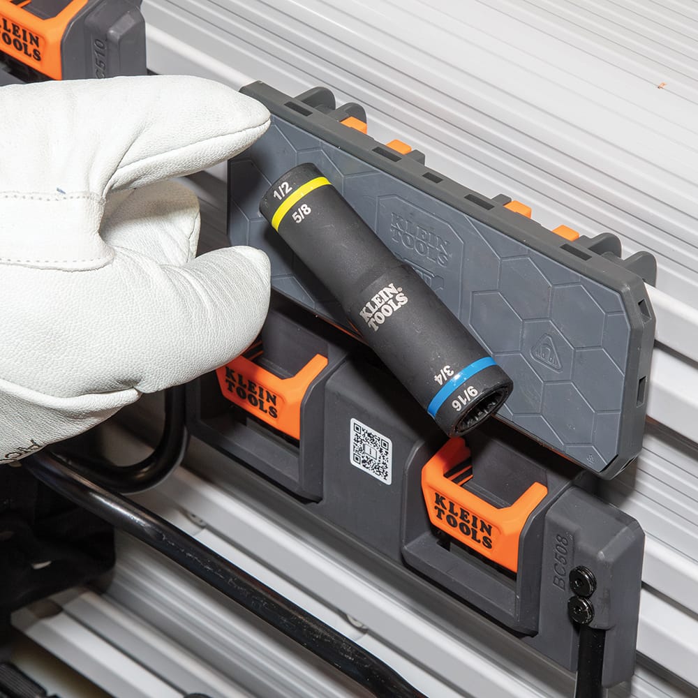 Gloved worker selecting a Klein 66009 4-in-1 flip quad socket stored on a bucket truck organizer rack for overhead utility line work.