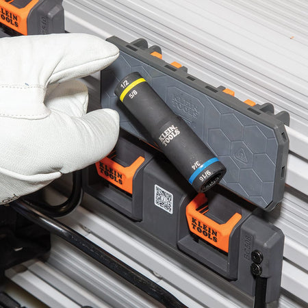 Gloved worker selecting a Klein 66009 4-in-1 flip quad socket stored on a bucket truck organizer rack for overhead utility line work.