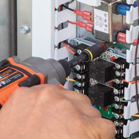 Electrician using the 3-inch magnetic Klein 32766 flip socket on a power driver to reach terminal board screws inside a control cabinet.