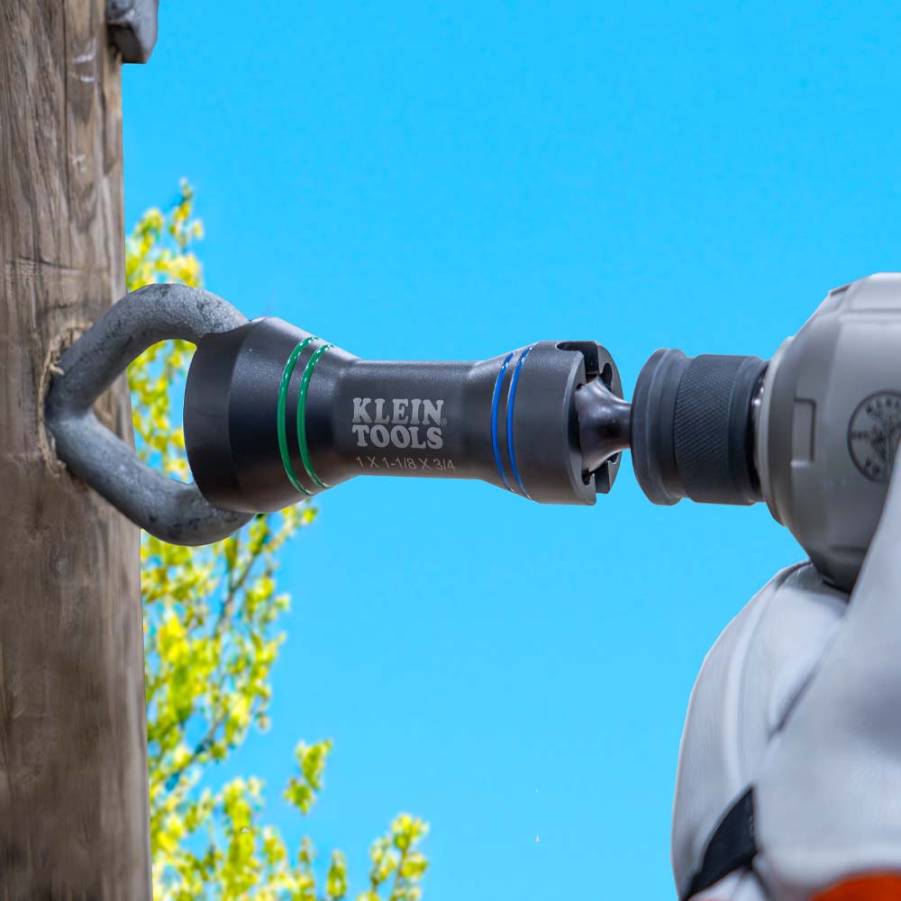 Lineman driving a heavy-duty steel eye bolt into a wooden utility pole using the slotted end of the Klein NRHDM socket.