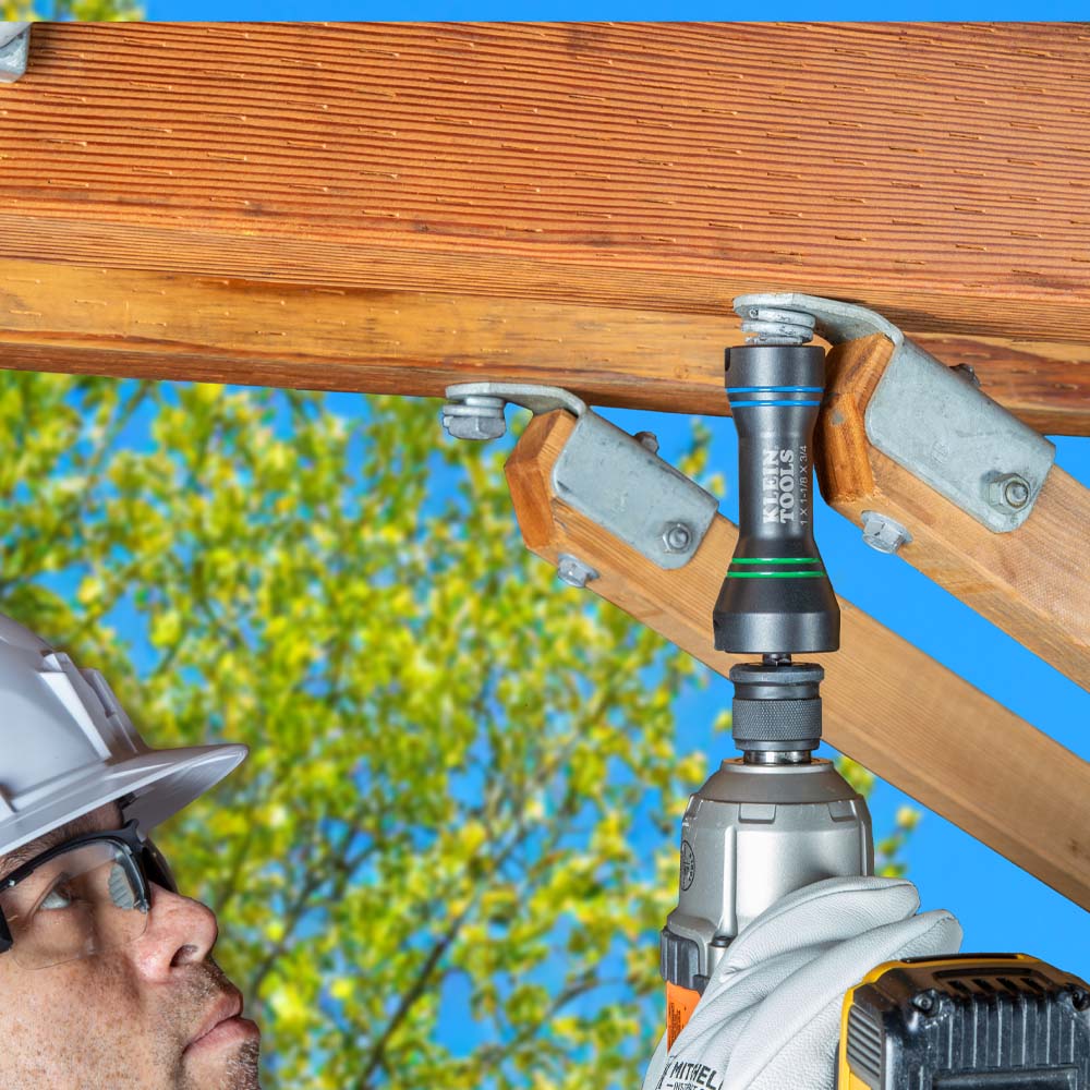 Aerial utility worker driving wooden crossarm bracket hardware overhead using the compact Klein NRHDM impact socket.