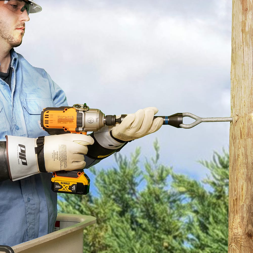 Lineman in insulated safety gloves driving a utility pole eye bolt using the alignment slot on the Klein NRHD socket.