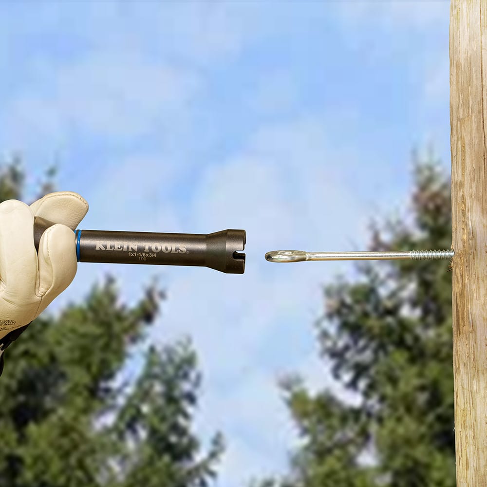 Lineman positioning the 6-inch hollow shaft of the Klein NRHD socket over a long threaded pole bolt in an aerial bucket.