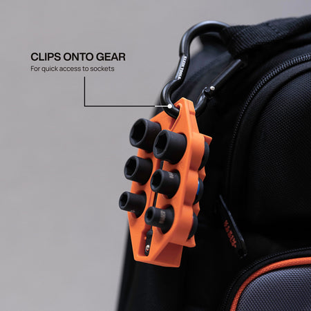 Klein Grab-And-Go socket holder clipped onto a tool backpack using an aluminum carabiner to demonstrate portable jobsite storage.