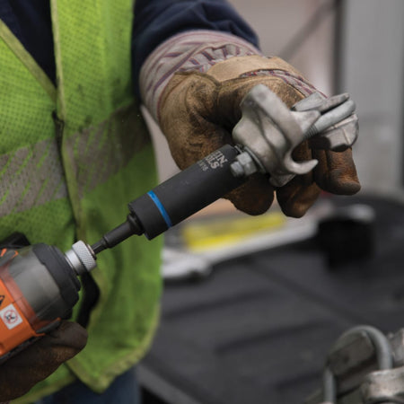 Utility worker using a Klein 3/4 by 9/16-inch coaxial socket on an impact driver to tighten overhead pole line mounting hardware.