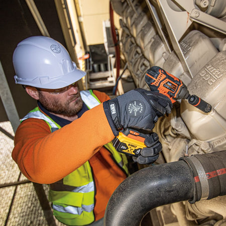 Industrial technician using a Klein 6-point coaxial socket on an impact driver to secure engine housing bolts in tight spaces.