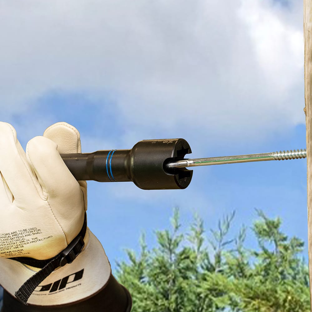 Gloved lineman using the side slot of the NRHD4 socket to align and thread a long screw-in hardware shaft on a utility pole.