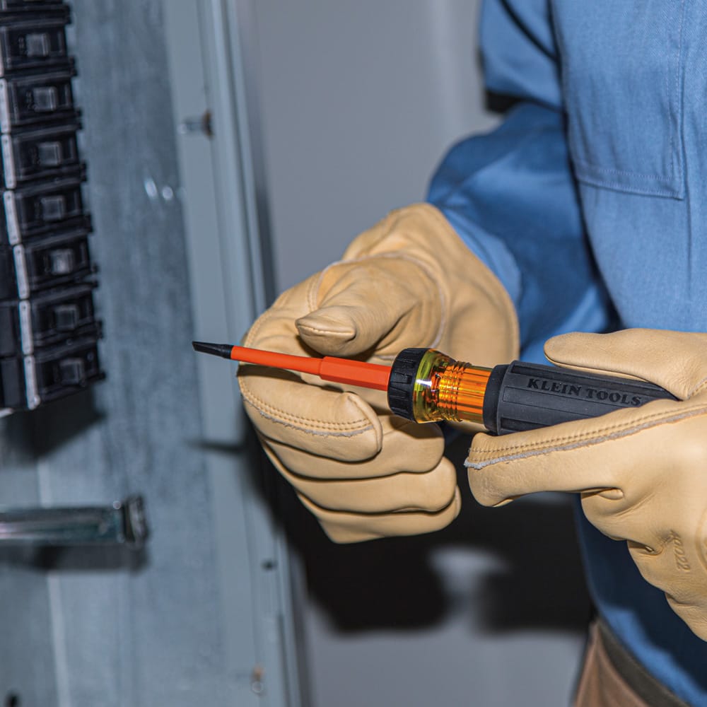 Electrician using the 3/16-inch slotted tip on the Klein 32286 insulated driver to adjust circuit breaker screws inside an electrical panel.