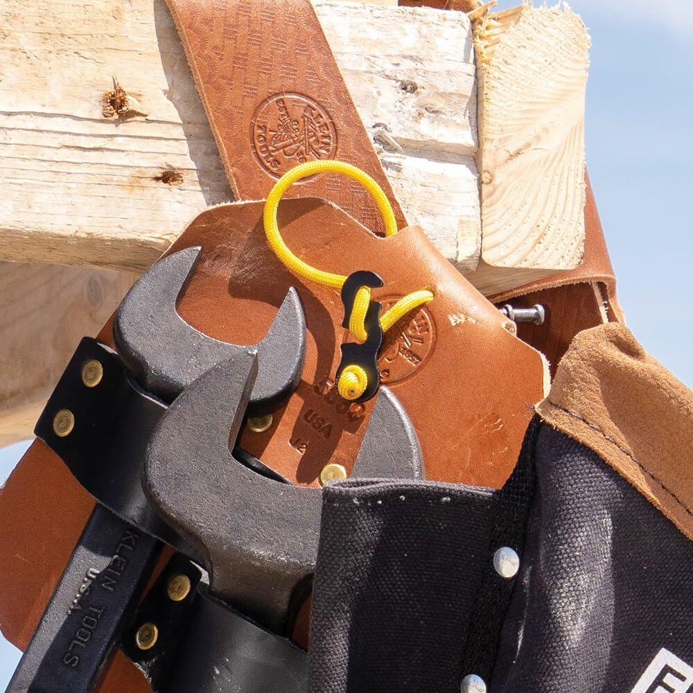 Close-up of the full-grain leather tool holders on the belt, showing spud wrenches secured in their dedicated holders next to the bolt bag on a construction site.