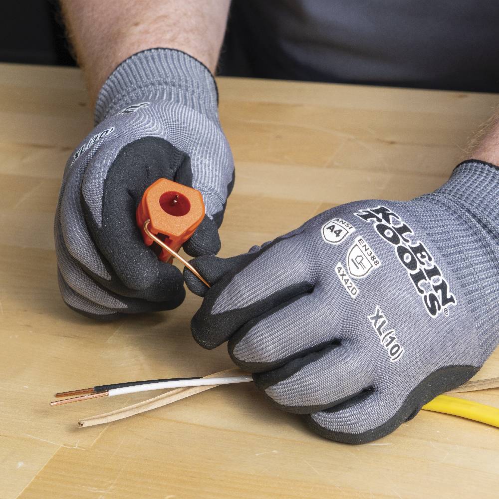 A close-up of a bare copper wire being bent using the tool's looping hole to create a J-hook for terminal connection.