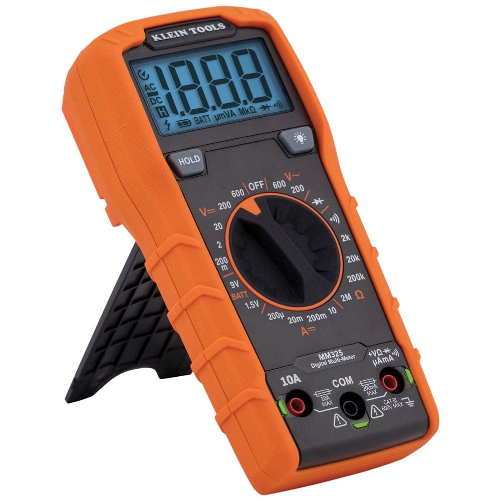 Angled three-quarter view of the MM325 multimeter standing upright on its integrated black kickstand. The device is shown from the left side, highlighting the rugged orange protective overmold and the clear markings on the central function selector dial.