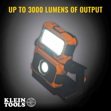 High-contrast image of the Klein Tools 56417 dual beam light powered on, with text overlay reading Up to 3000 Lumens of Output. Both the wide-angle flood light and the concentrated spot light are illuminated, demonstrating maximum brightness for dark work areas.