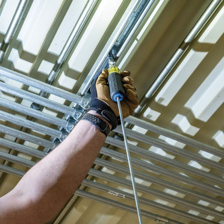 Electrician using the Klein 32809MAGM pass-through driver overhead to run metric nuts up a long threaded rod on strut channel.