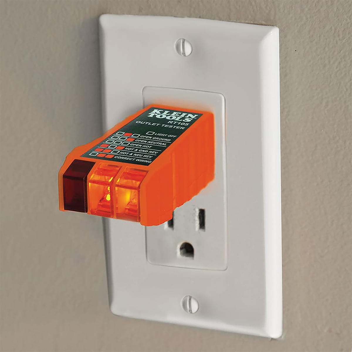 A professional application shot showing the RT105 receptacle tester plugged into a standard white wall outlet. Two orange LEDs are illuminated on the device, providing a clear visual confirmation of a correctly wired electrical circuit in a residential or commercial setting.