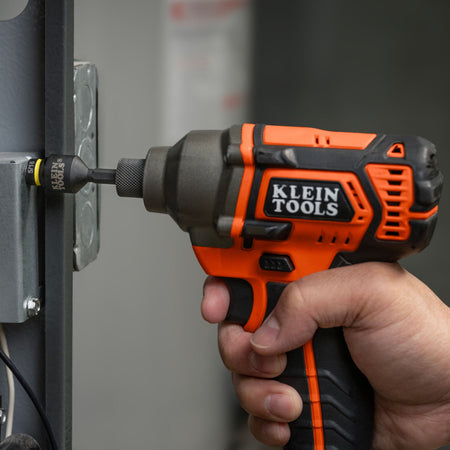 Electrician using a 1/4-inch impact driver with a Klein 5/16-inch socket to rapidly secure a metal electrical box panel screw.