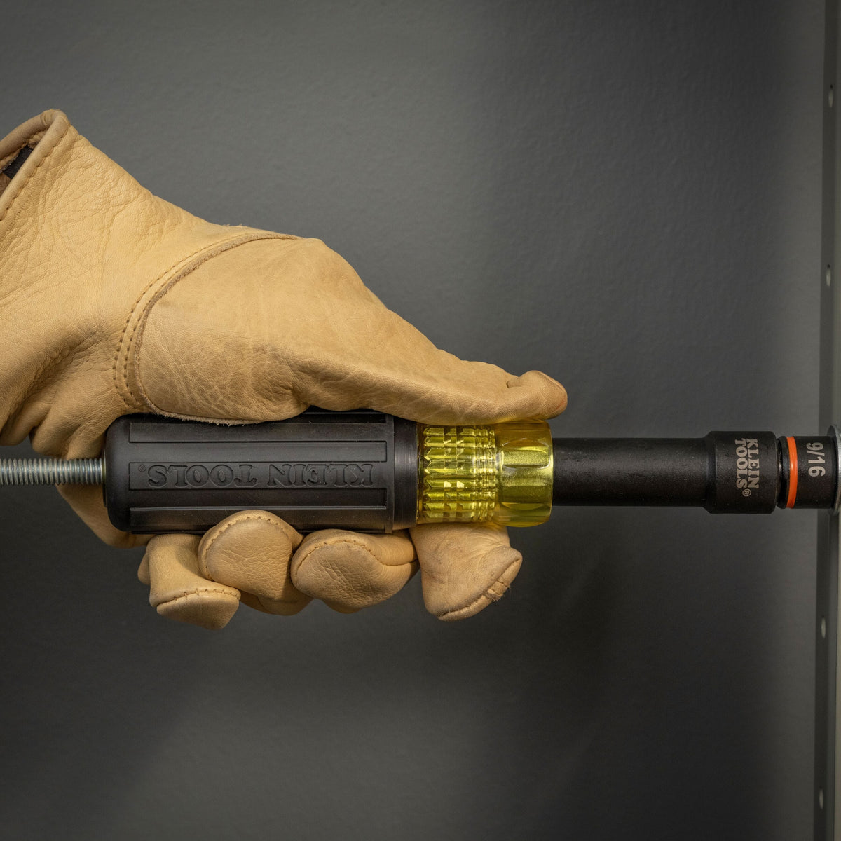 Contractor using the Klein hollow Cushion-Grip handle and a 9/16-inch socket to drive a hex nut over a long threaded rod.