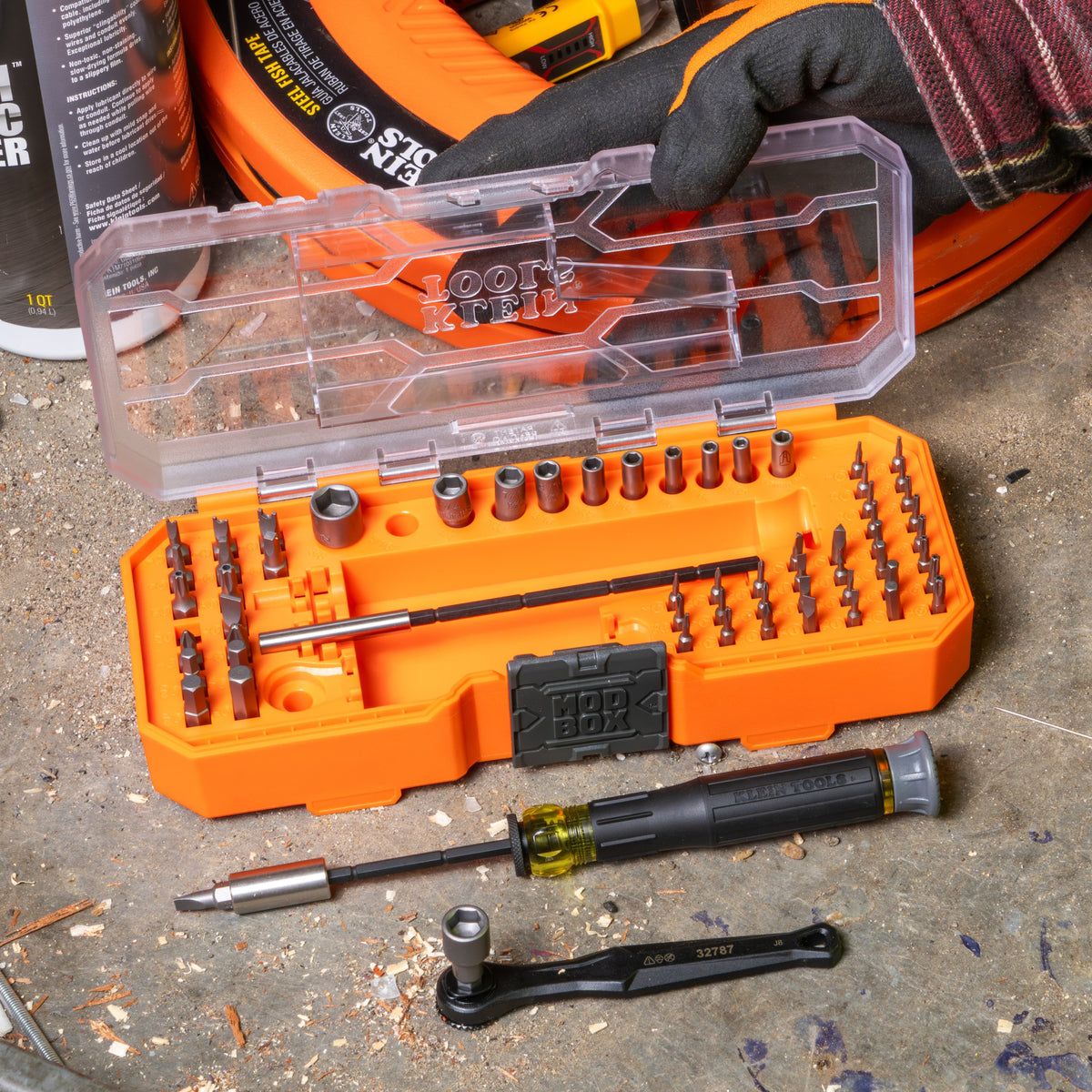 Klein 32787 precision ratchet and driver kit unpacked on a jobsite surface alongside fish tape and wire pulling lubricant.
