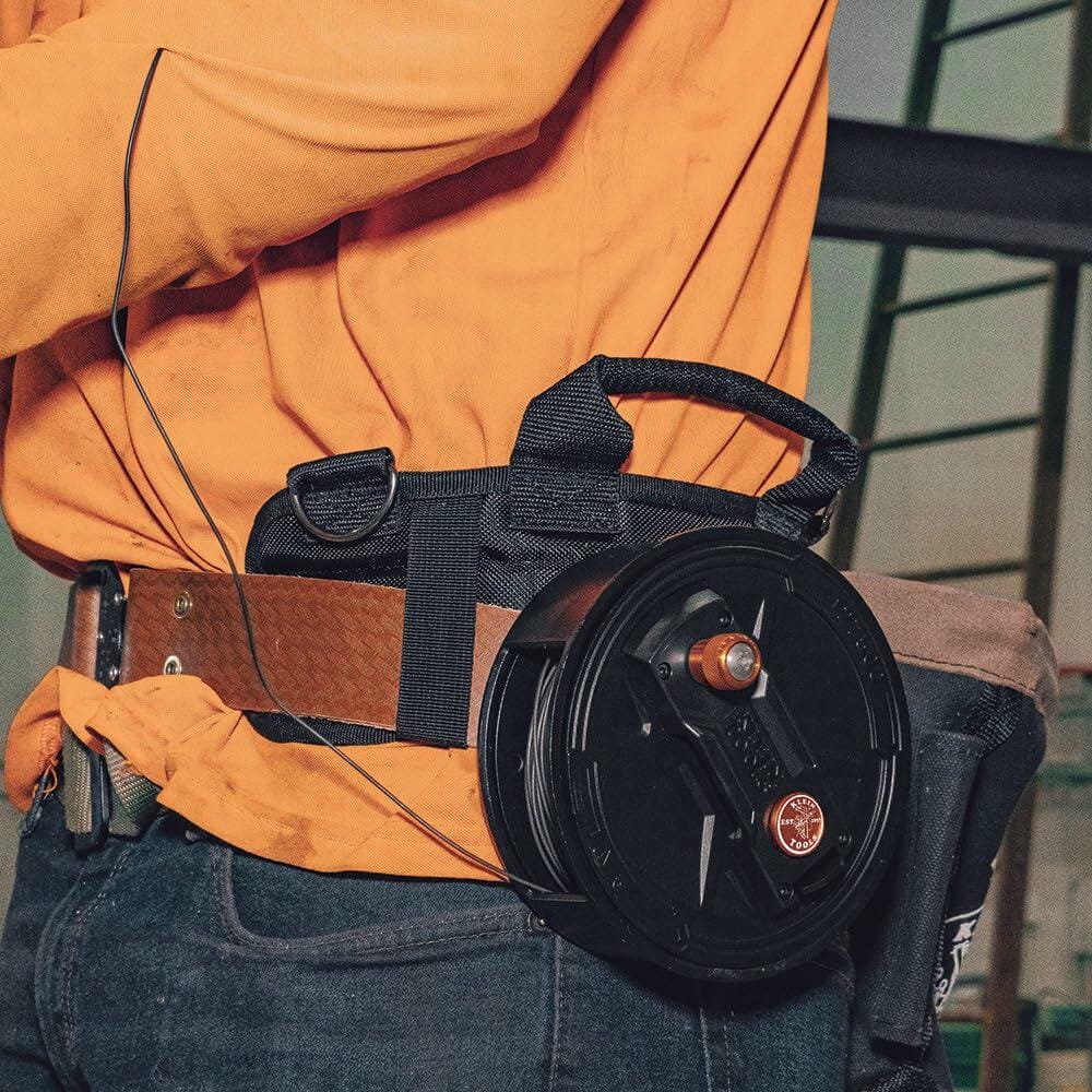 The Klein Tools Tie Wire Reel on a worker's belt dispenser, showing the tie wire dispensing smoothly and quickly for rebar or masonry work.