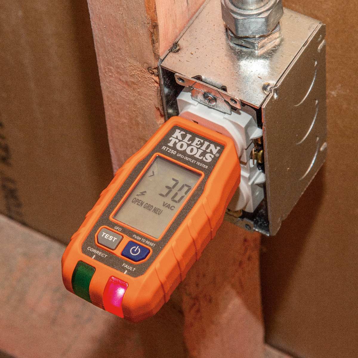 Action shot of the RT250 Receptacle Tester plugged into a standard residential wall outlet. The backlit LCD is active, displaying a precise real-time voltage reading of 121V and confirming a correct wiring condition with clear text indicators.