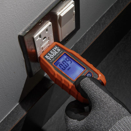 Action shot showing a technician using the NCVT3P non-contact tester to verify power at an electrical junction box. The integrated LED flashlight is activated to illuminate the workspace, while the sensing tip identifies a live wire without making physical contact.