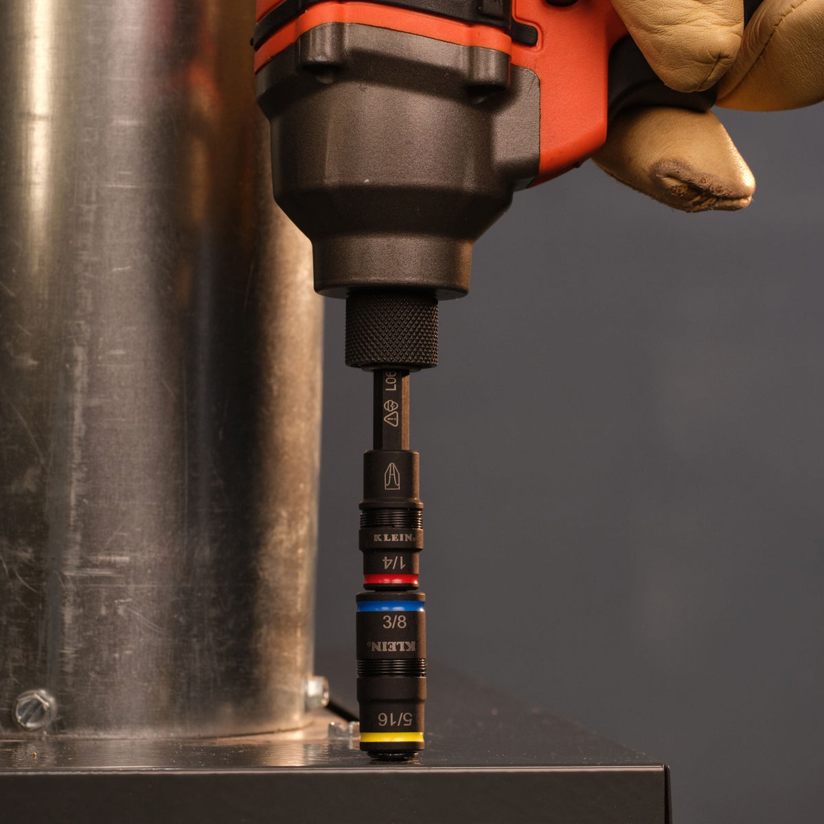 Worker using an impact driver with the Klein Tools 32517HD bit shaft to drive fasteners next to a metal duct pipe.