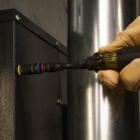 Contractor using the Klein Tools 32517HD screwdriver with 5/16-inch flip socket to secure an HVAC metal equipment cabinet panel.