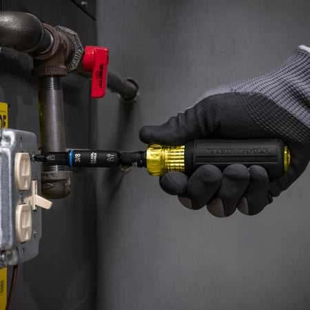 Technician using the Klein Tools 32527HD multi-bit screwdriver to tighten an electrical cover screw near an HVAC gas line unit.