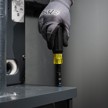 Technician using the Klein 32527HD screwdriver to drive a 3/8-inch hex head fastener on a commercial HVAC unit cabinet top.